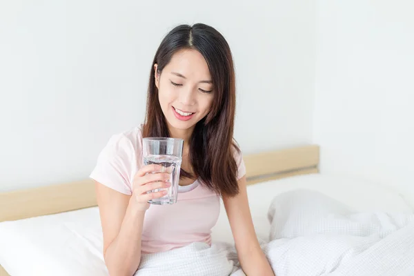 Женщина пьет воду и сидит на кровати — стоковое фото