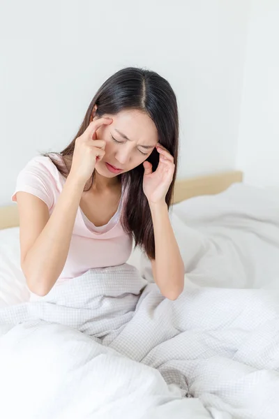 Mujer sintiendo dolor de cabeza y sentada en la cama —  Fotos de Stock