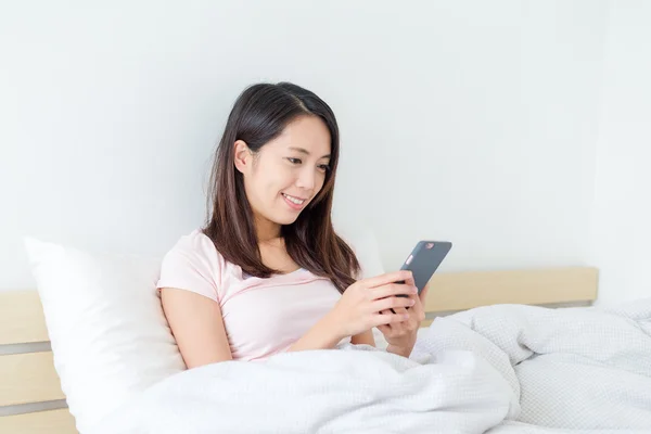 Mulher usando celular e sentado na cama — Fotografia de Stock