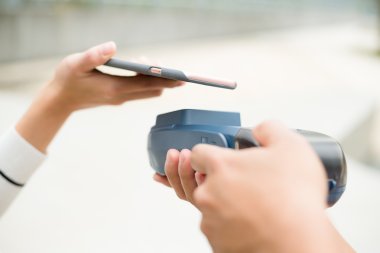 Woman using smart phone for paying the bill