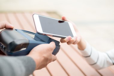 Woman using smart phone for paying the bill