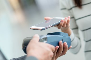 Woman using smart phone for paying the bill