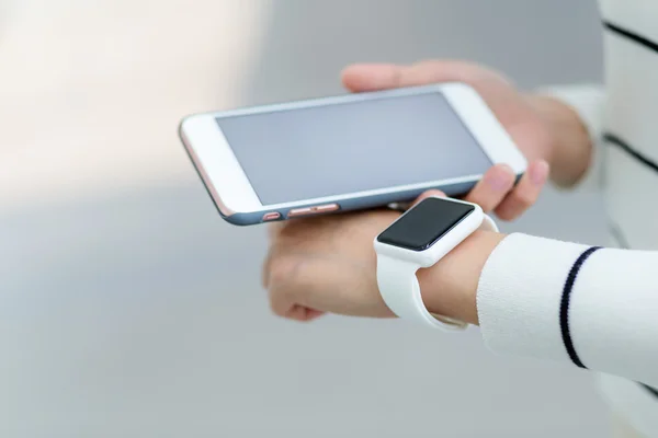 Vrouw verbinden met mobiel en slimme horloge — Stockfoto