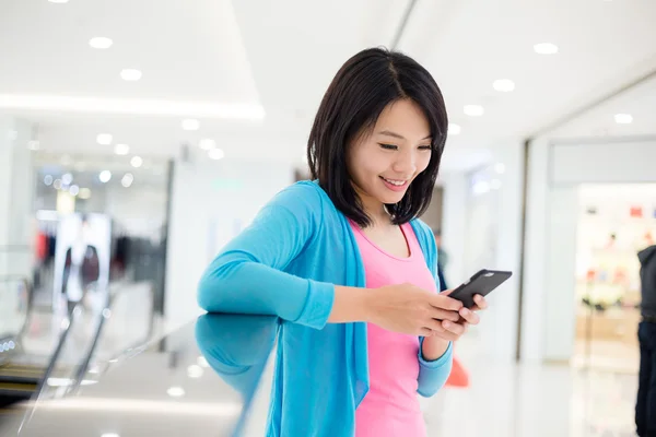 Žena používající mobilní telefon v obchodním domě — Stock fotografie