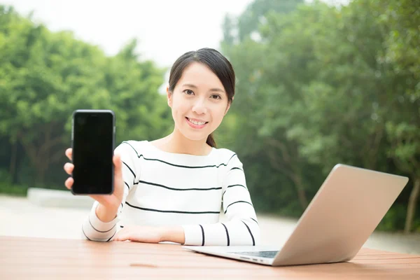 Mujer con portátil que muestra la pantalla en blanco del teléfono celular —  Fotos de Stock