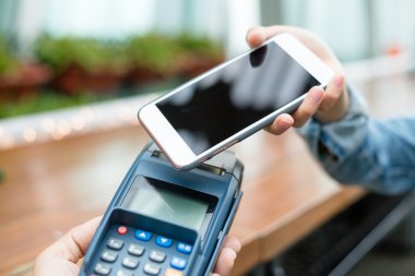 Woman using smart phone for paying the bill