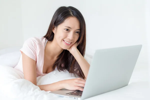 Vrouw met laptop werkt en liggend op bed — Stockfoto