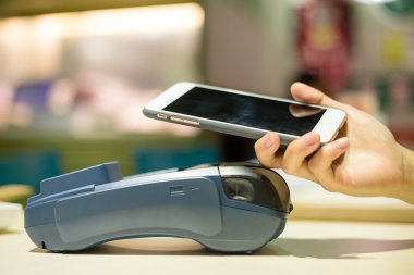 Woman using smart phone for paying the bill