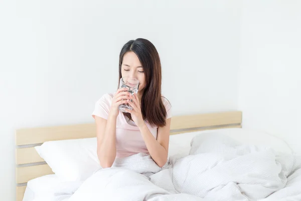 Mulher tomando um copo de água na cama — Fotografia de Stock