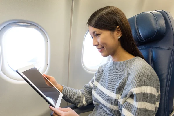 Vrouw die tablet pc gebruikt in vliegtuig — Stockfoto