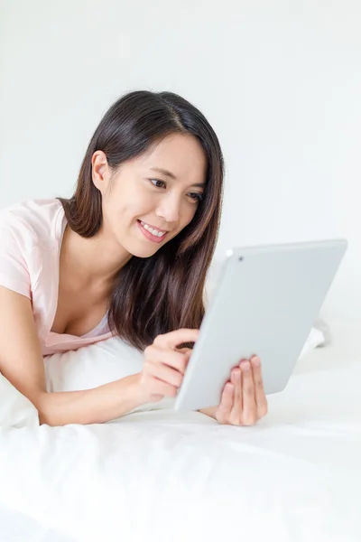 Frau benutzt Tablet-PC und liegt im Bett — Stockfoto