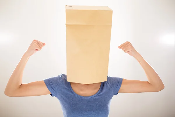 Chica con bolsa cubriendo su cabeza y mostrando sus bíceps — Foto de Stock