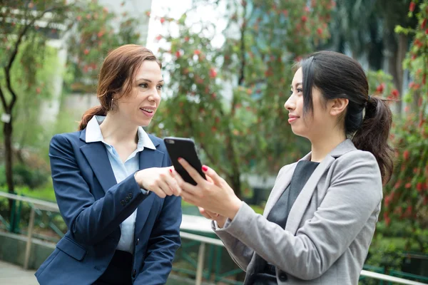 Mulheres de negócios discutindo algo no celular — Fotografia de Stock