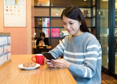 Cep telefonu kullanarak ve kahvaltı yapıyor kadın