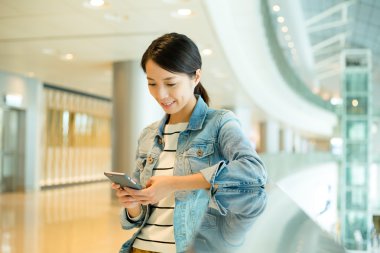 alışveriş merkezinde cep telefonu kullanan kadın