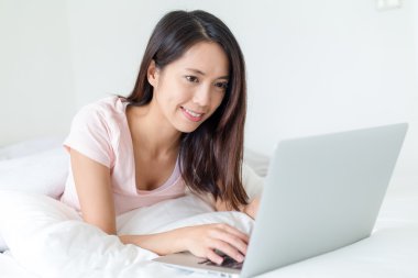 Yatakta laptop kullanan bir kadın