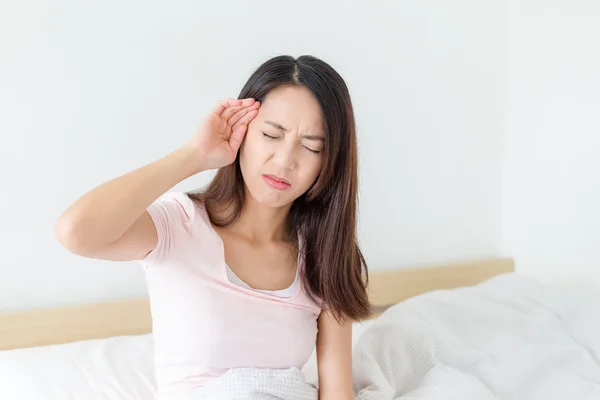 Frau mit Kopfschmerzen sitzt auf ihrem Bett — Stockfoto