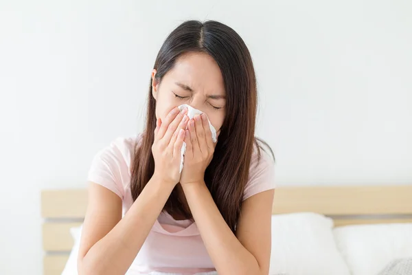 Sick woman sneezing into tissue — Stock Photo, Image