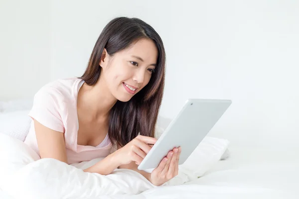 Lachende vrouw met tablet op haar bed — Stockfoto