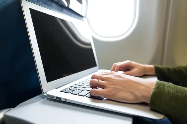 Woman using laptop in airplane — Zdjęcie stockowe