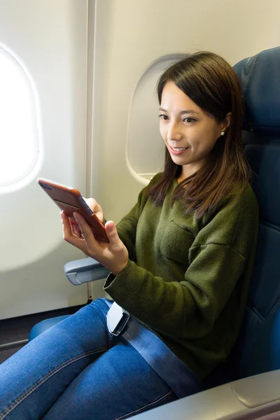 Vrouw met behulp van de mobiele telefoon in vliegtuigen — Stockfoto