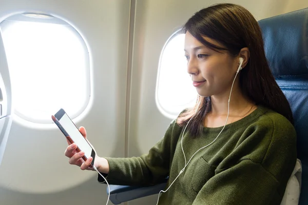 Donna che ascolta musica sul cellulare all'interno dell'aereo — Foto Stock