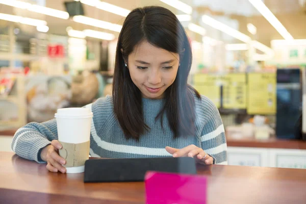 Kadın kahve içiyor ve tablet kullanıyor. 