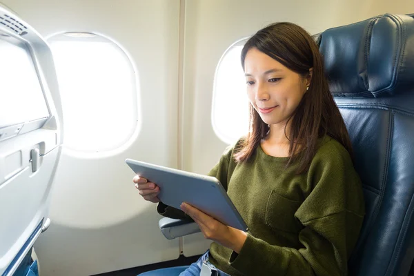 Vrouw met behulp van tablet pc in vliegtuig — Stockfoto