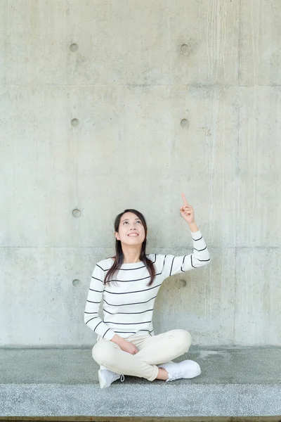 Woman sitting and pointing up with finger — Stock Photo, Image