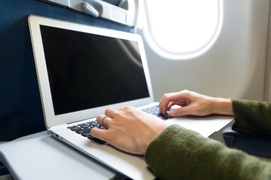 Uçak içinde laptop üzerinde çalışan kadın