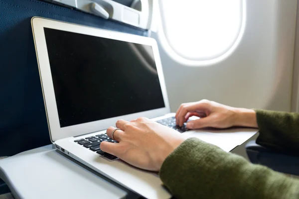 Жінка працює на ноутбуці в літаку — стокове фото