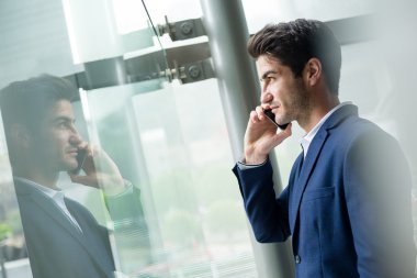 pencerenin yakınındaki smartphone cep telefonu ile konuşurken işadamı