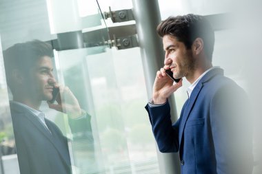 pencerenin yakınındaki smartphone cep telefonu ile konuşurken işadamı