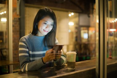 Kahve Kupası'nda cep telefonu kullanan kadın