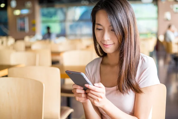 Vrouw met behulp van slimme telefoon in overdekte café — Stockfoto