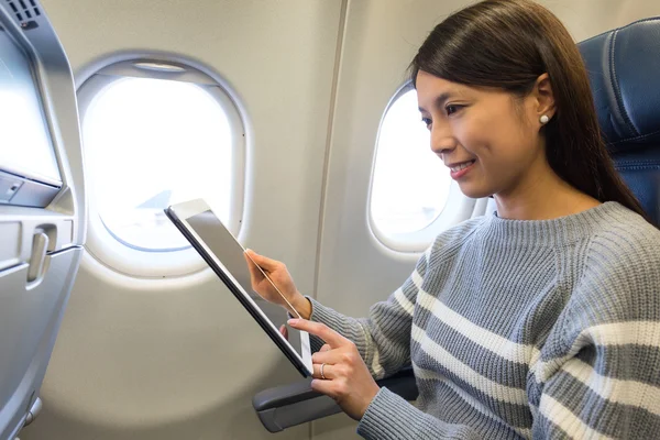 Vrouw met behulp van de tablet in vliegtuig — Stockfoto