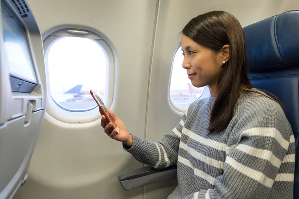 Mujer con teléfono celular dentro del avión — Foto de Stock
