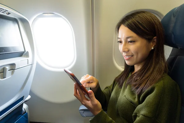 Woman using mobile phone inside airplane — Stock Photo, Image