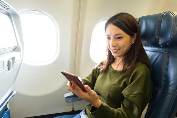 Woman using smart phone inside airplane — Stock Photo, Image