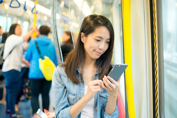 Kvinna med mobiltelefon inne i tåget — Stockfoto