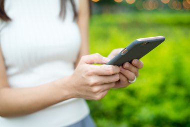 Kadın cep telefonu elinde tutar.