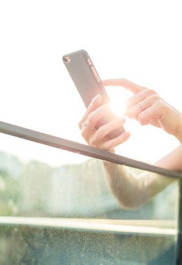 Günbatımı altında cep telefonu kullanan kadın