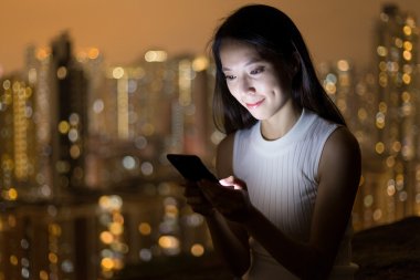 Geceleri cep telefonu kullanan bir kadın.