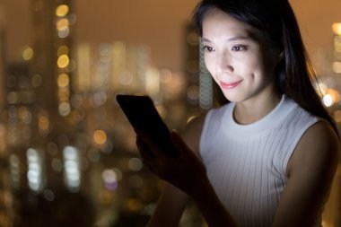 Geceleri cep telefonu kullanan bir kadın.