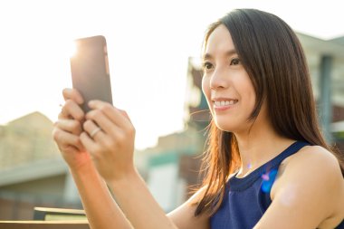 Cellphine güneş ışığı altında kullanan kadın