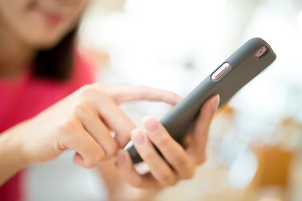 Vrouw die bladeren van de mobiele telefoon in café — Stockfoto