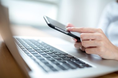 bir cep telefonu ve dizüstü bilgisayar kullanan kadın
