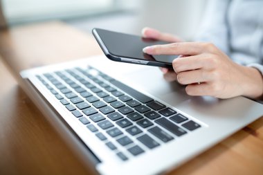 Kadın el cep telefonu ve dizüstü bilgisayar kullanarak