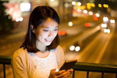 Geceleri cep telefonu kullanan bir kadın.