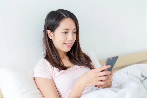 Egy nő mobilt használ az ágyban. — Stock Fotó